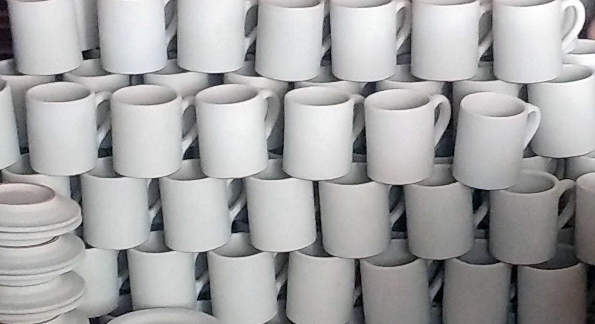 Gestapelte weiße glasierte Kaffeebecher in einer Werkstatt
