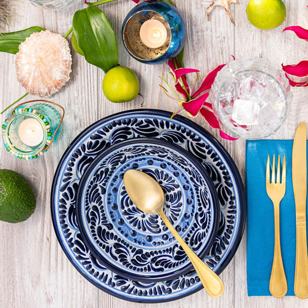 Gedeckter Tisch zum Abendessen mit blau-weißem mexikanischen Geschirr, Oliven, Muscheln und Limetten Ausschnitt
