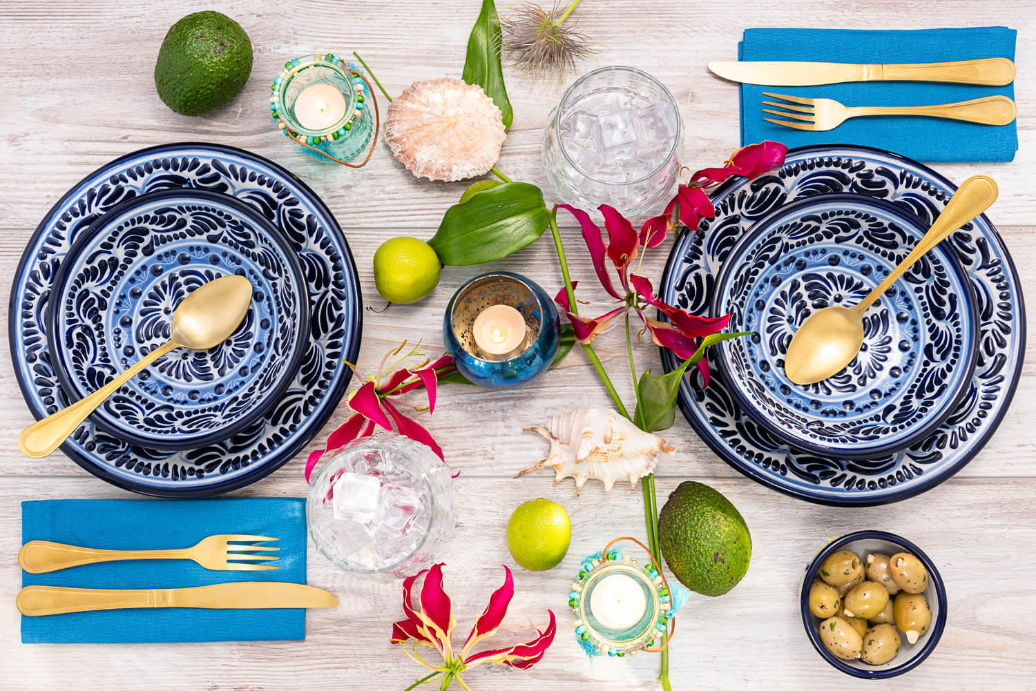 Gedeckter Tisch zum Abendessen mit blau-weißem mexikanischen Geschirr, Oliven, Muscheln und Limetten