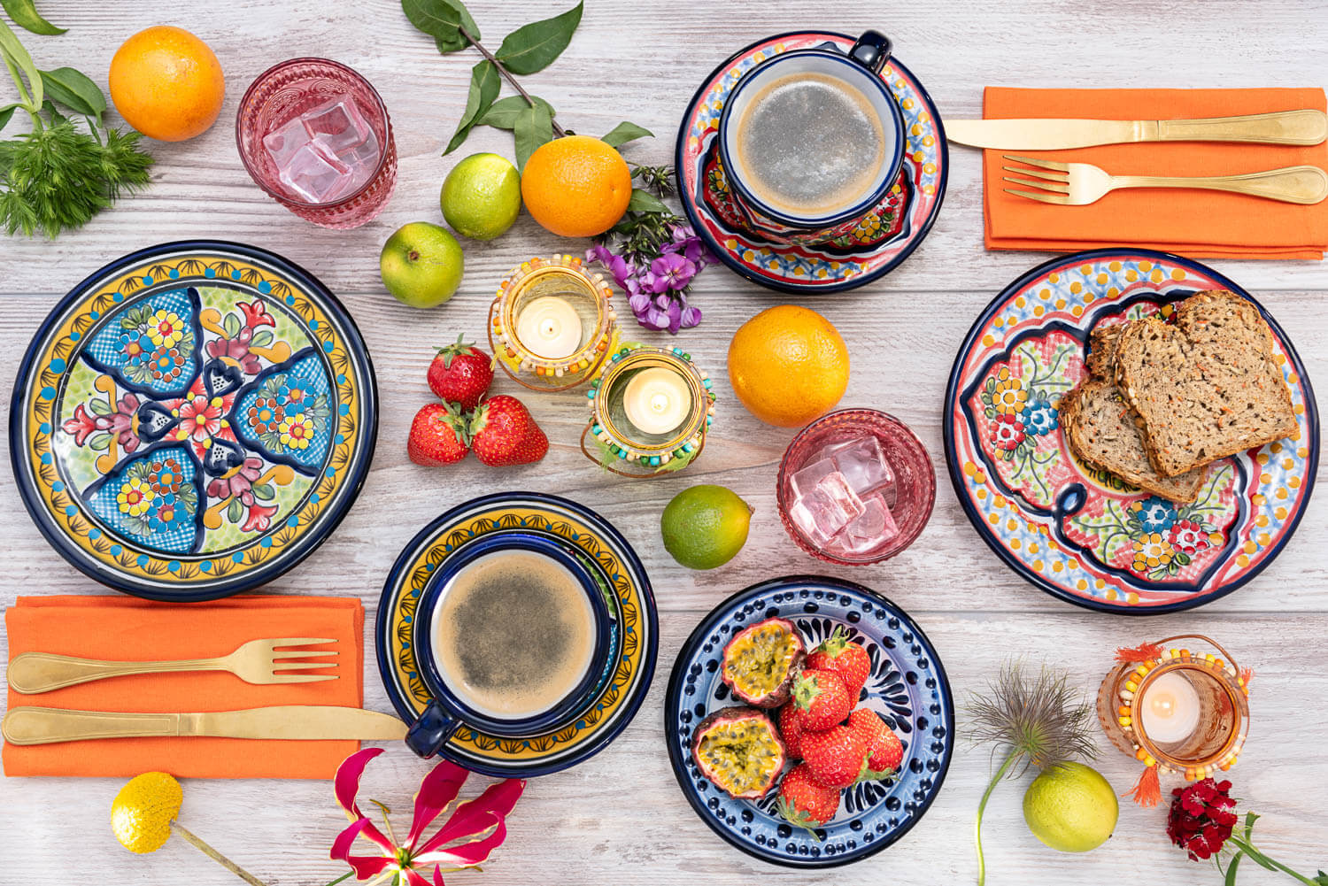 Gedeckter Tisch zum Frühstück mit buntem mexikanischen Geschirr, Obst und Blumen