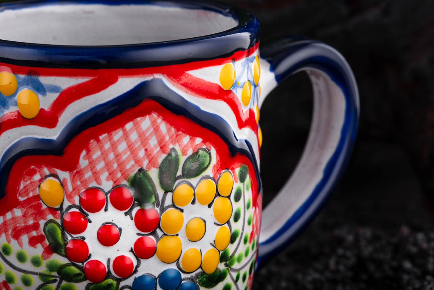 bunter Kaffeebecher rot-blau-gelb mit Blumen auf Schieferplatte Detailansicht