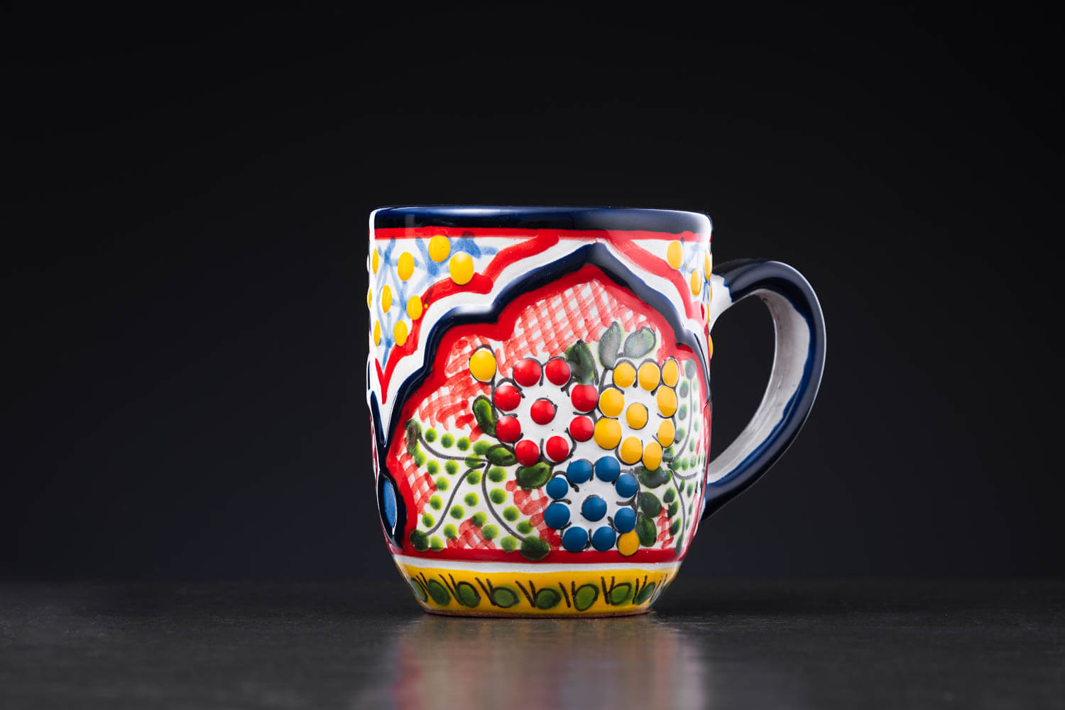 bunter Kaffeebecher rot-blau-gelb mit Blumen auf Schieferplatte Rückansicht