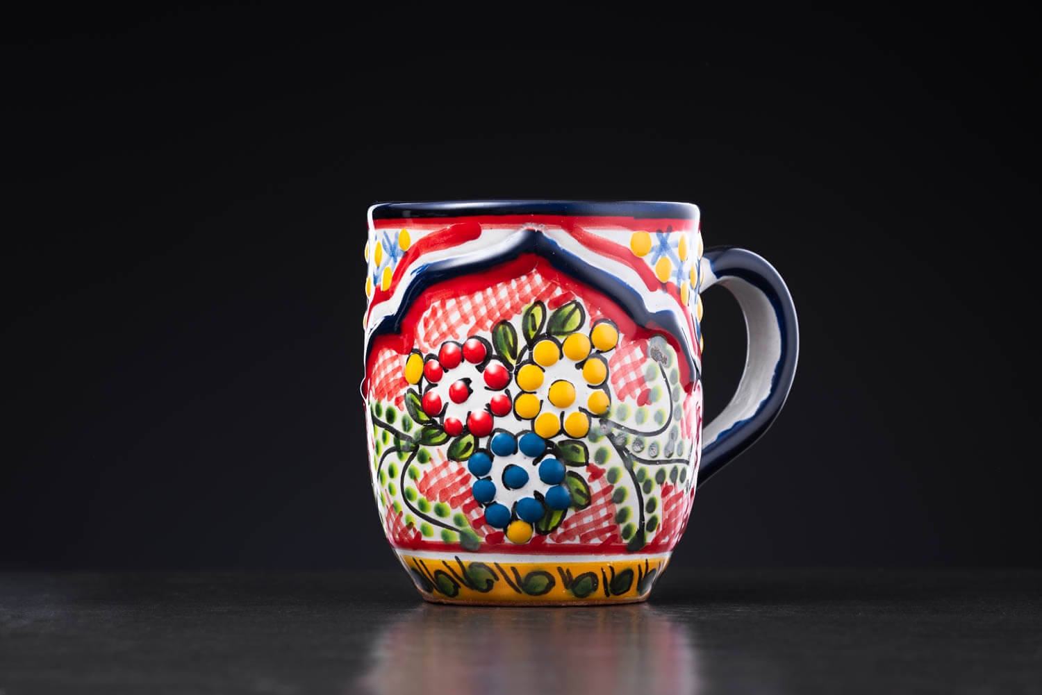 bunter Kaffeebecher rot-blau-gelb mit Totenkopf und Blumen auf Schieferplatte Rückansicht