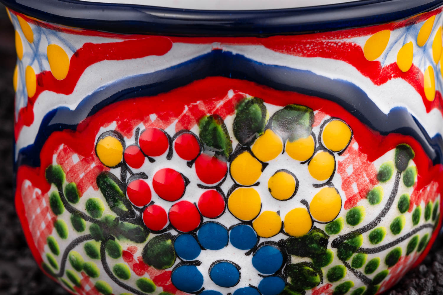 bunte Kaffeetasse rot-blau-gelb mit Blumen auf Schieferplatte Detailansicht