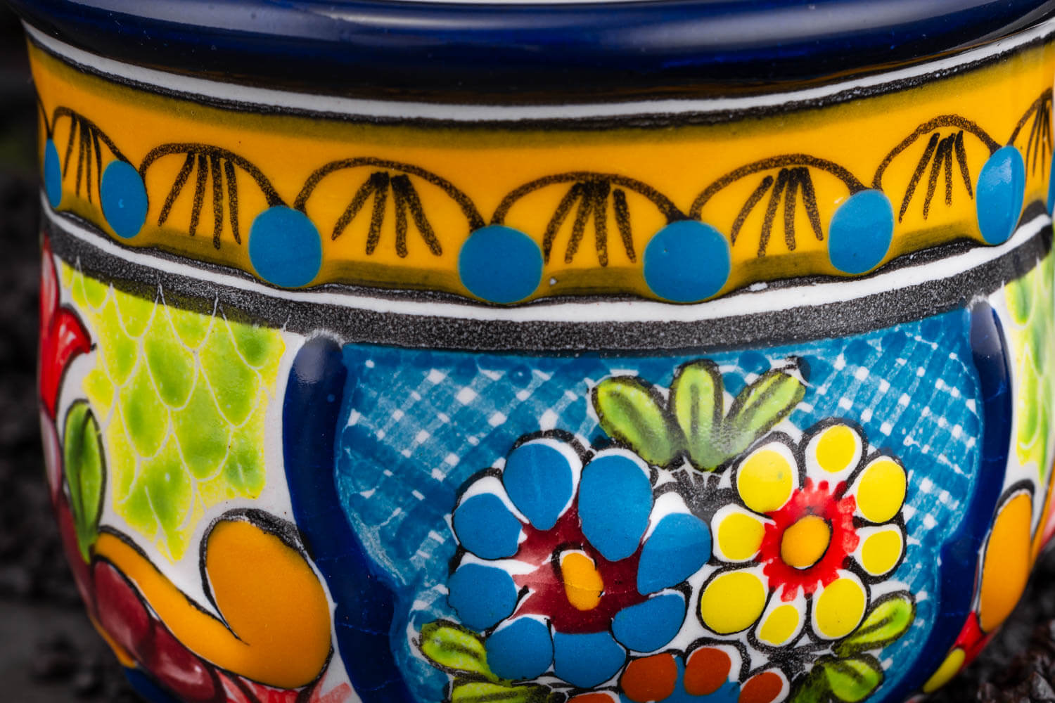 bunte Kaffeetasse blau-grün-gelb mit Blumen auf Schieferplatte Detailansicht
