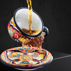 Set bunte Kaffeetasse und Untertasse rot-blau-gelb mit Blumen und eingegoßenem Tee vor mexikanischem Hintergrund