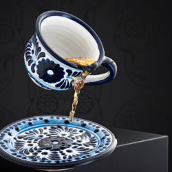 Set meeresfrische Kaffeetasse und Untertasse blau-weiß und eingegoßenem Tee vor mexikanischem Hintergrund