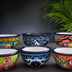 Set bunte Schalen und Schälchen mit Blumen auf Schieferplatte mit Palmenblättern