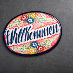 buntes Türschild rot-grün-gelb mit Blumen auf Schieferplatte